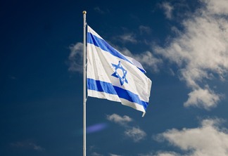 israel flag on a flagpole under the blue sky