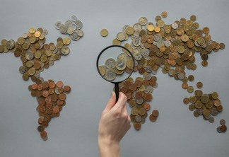 anonymous person with magnifying glass over world map of coins