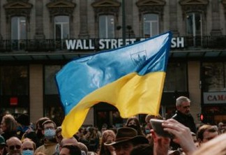 blue and yellow ukrainian flag waving above crowd of people