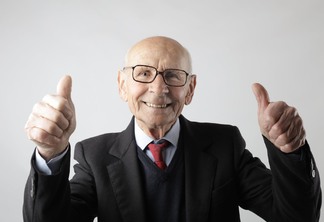 positive senior man in eyeglasses showing thumbs up and looking at camera