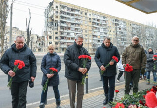 O Alto Comissário do ACNUR, Filippo Grandi (ao centro da foto), ao lado de representantes das autoridades locais, deposita flores em um prédio residencial que foi destruído durante um ataque com mísseis em 14 de janeiro de 2023, na cidade de Dnipro, Ucrânia. (© ACNUR/Colin Delfosse)